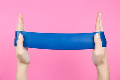 Woman with fitness elastic band on pink background, closeup