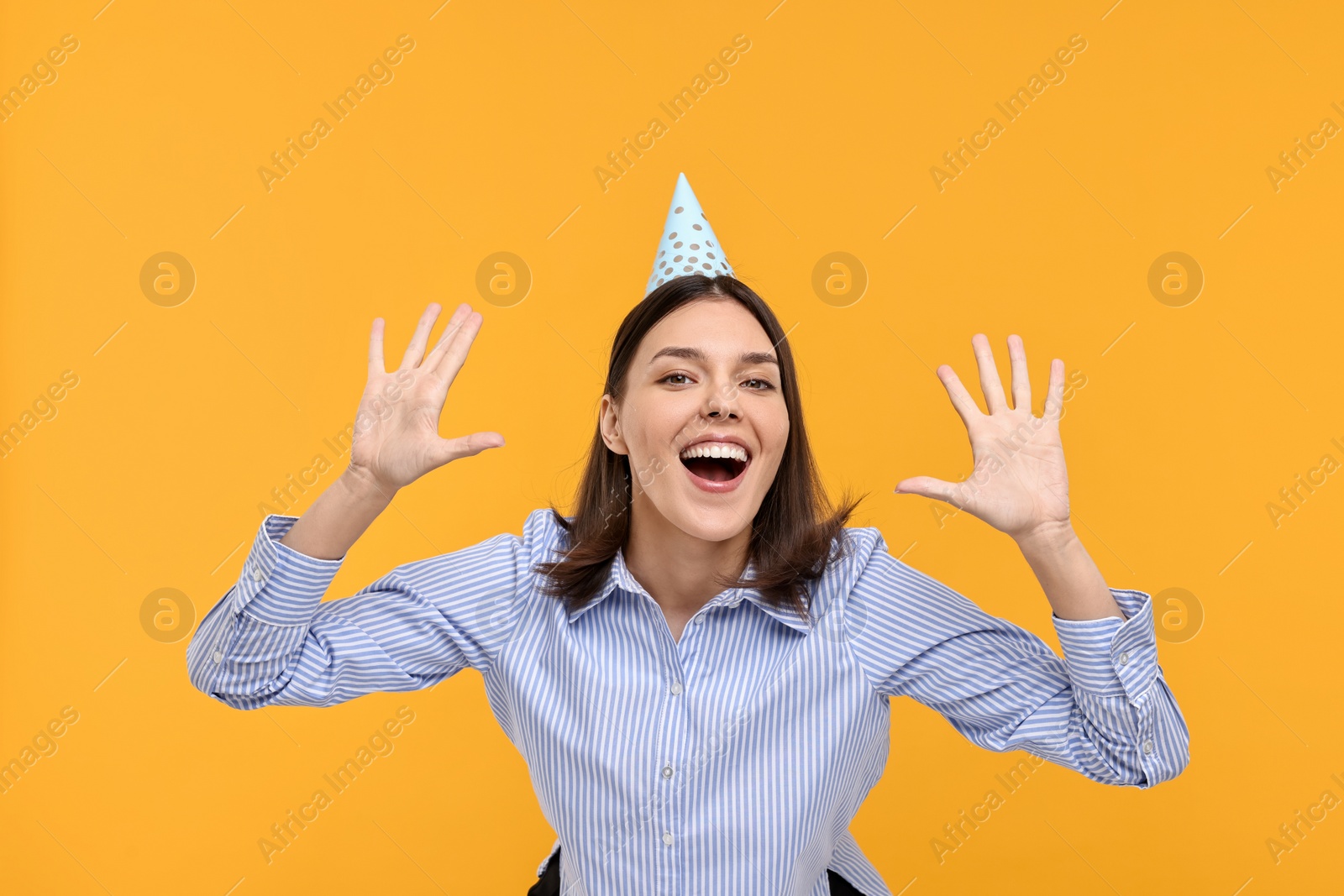 Photo of Happy young woman in party hat on yellow background