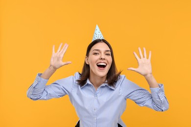 Happy young woman in party hat on yellow background