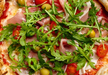 Photo of Tasty pizza with meat and arugula as background, top view