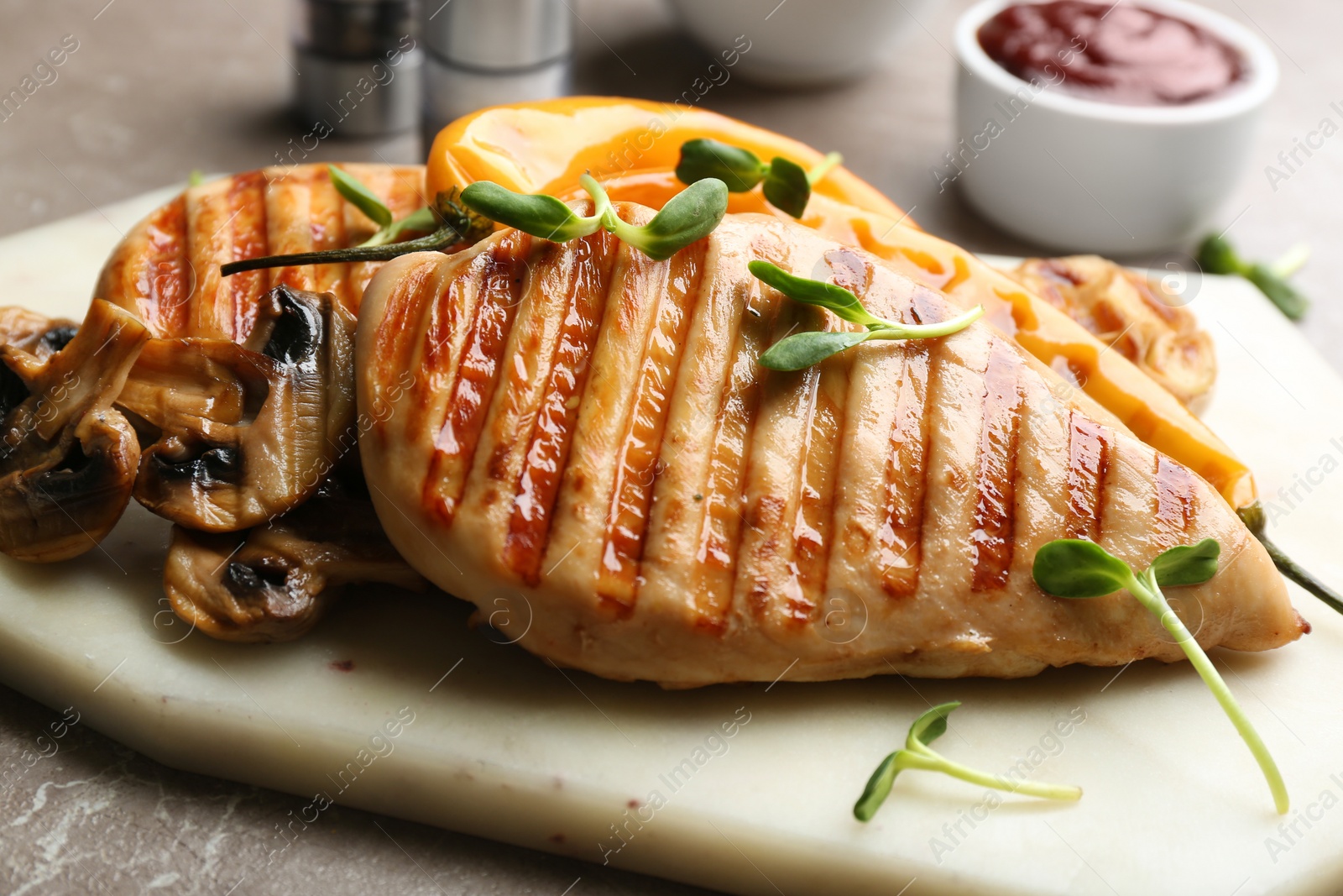 Photo of Tasty grilled chicken fillets with mushrooms and green sprouts on white marble board, closeup