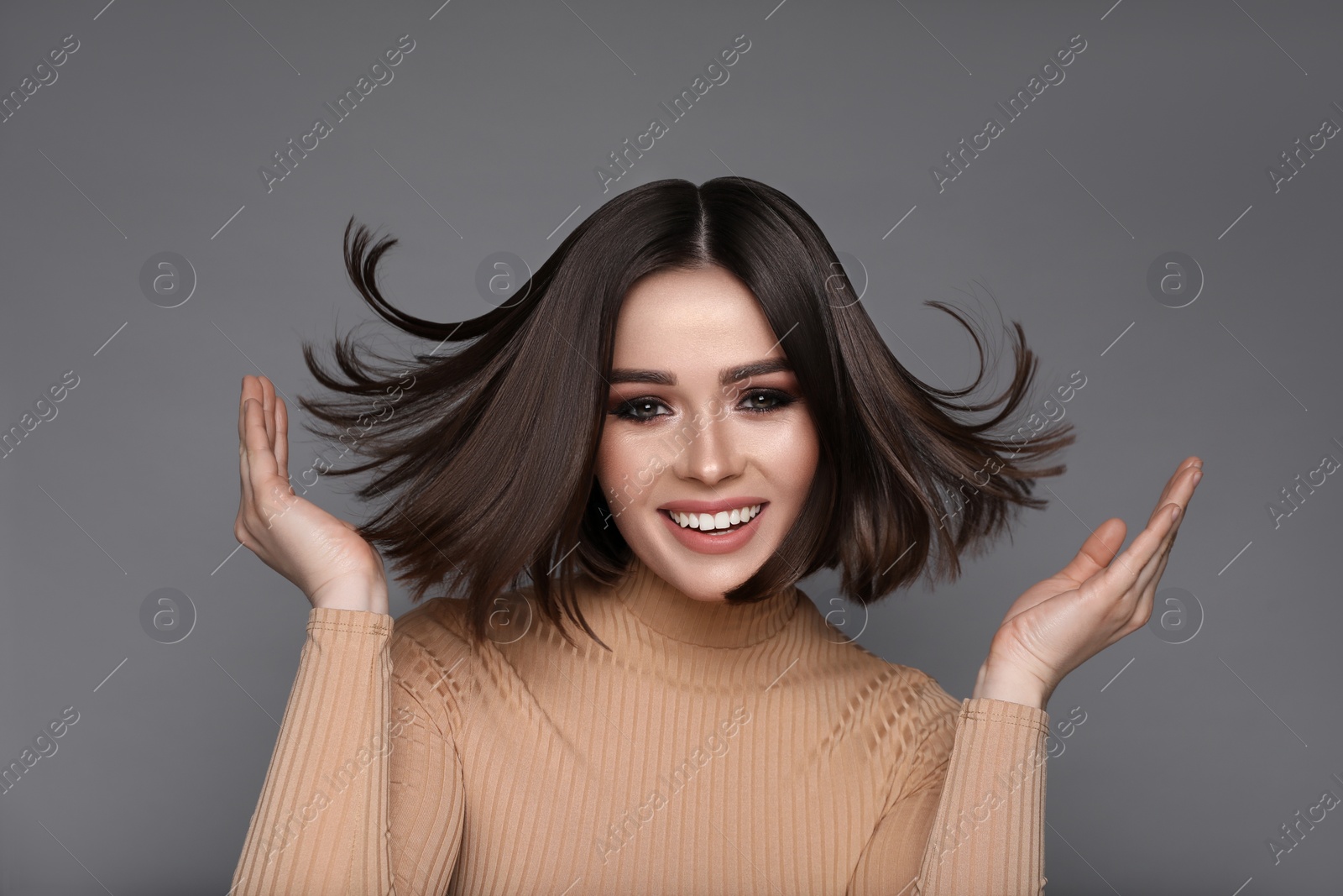 Image of Portrait of pretty young woman with brown hair smiling on grey background