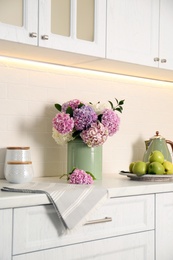 Photo of Beautiful hydrangea flowers and apples on light countertop