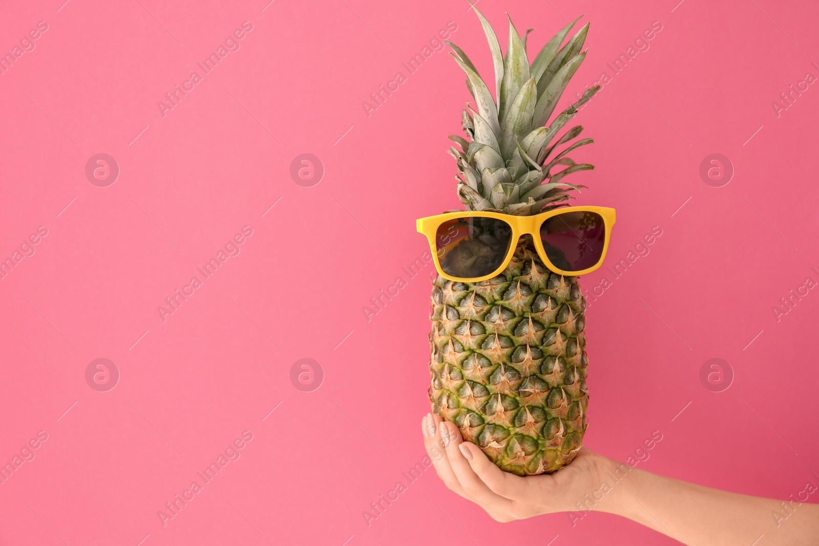 Photo of Woman holding fresh ripe pineapple with sunglasses on color background