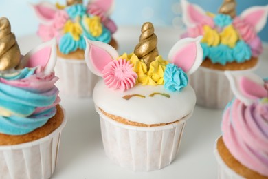 Photo of Cute sweet unicorn cupcakes on white table, closeup