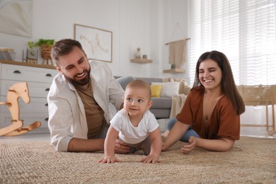 Photo of Happy parents watching their baby crawl on floor at home