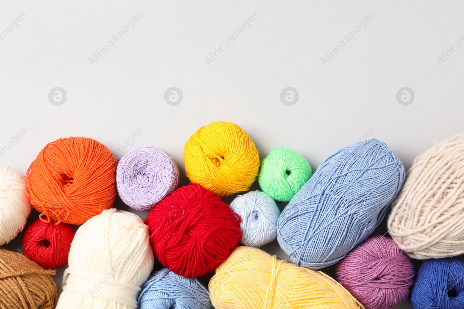 Photo of Different colorful woolen yarns on white background, flat lay. Space for text