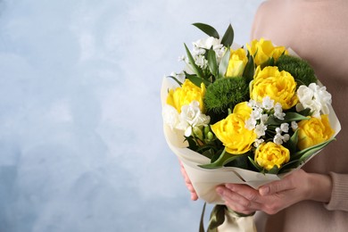 Photo of Woman with bouquet of beautiful tulips on light blue background, closeup. Space for text