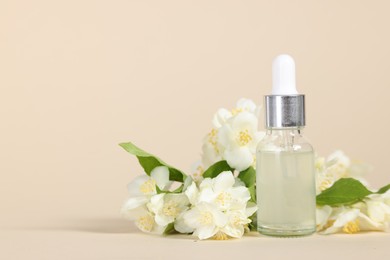 Photo of Essential oil in bottle and beautiful jasmine flowers on beige background, space for text