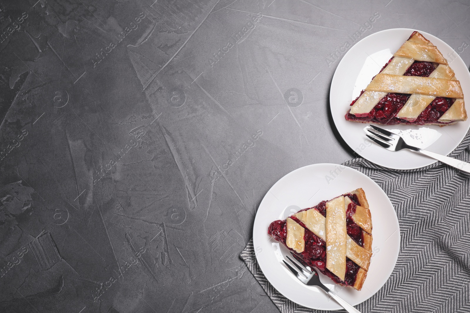 Photo of Slices of delicious fresh cherry pie served on grey table, flat lay. Space for text