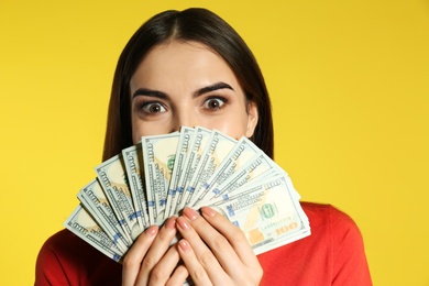 Young woman with money on color background