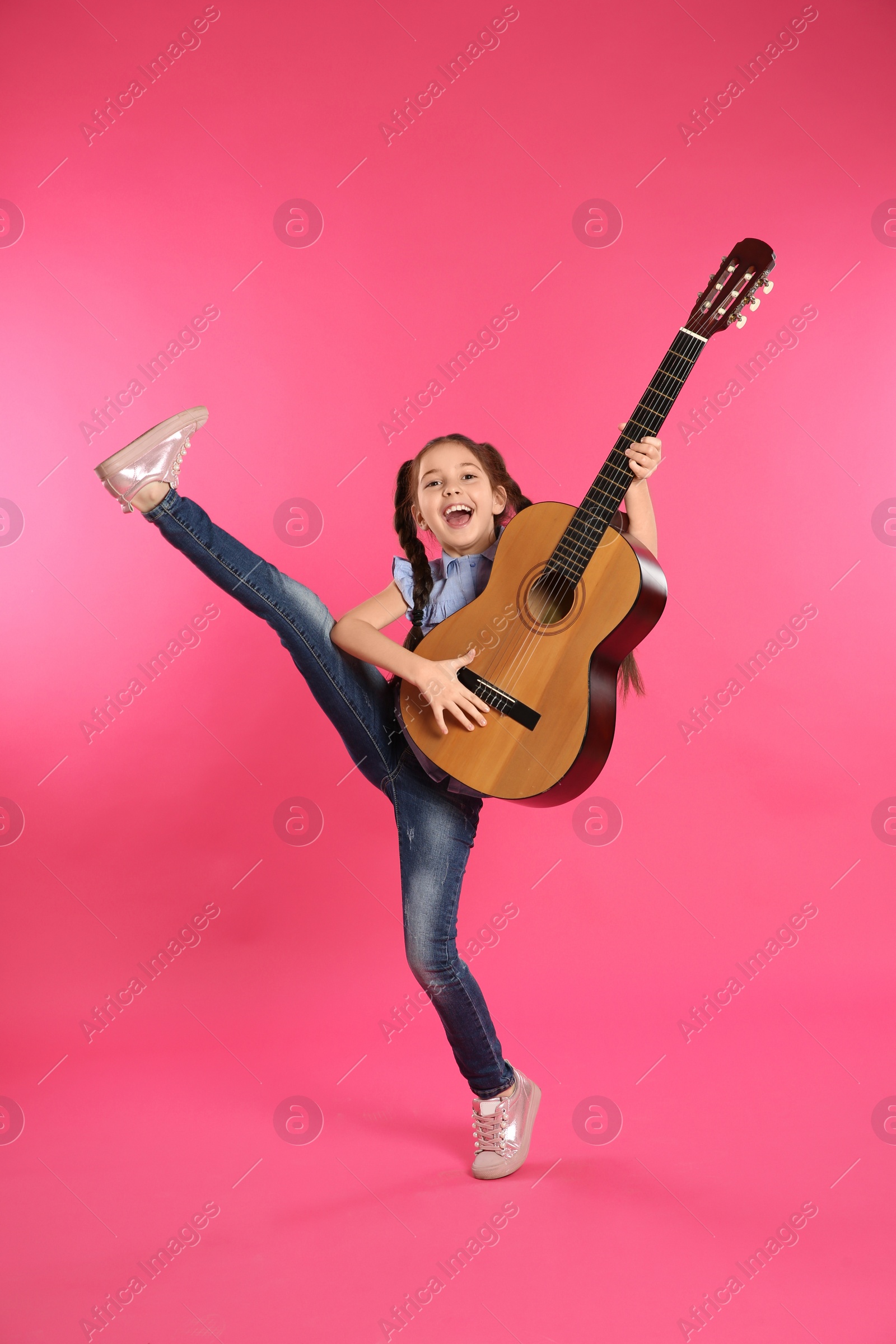 Photo of Cute little girl playing guitar on color background