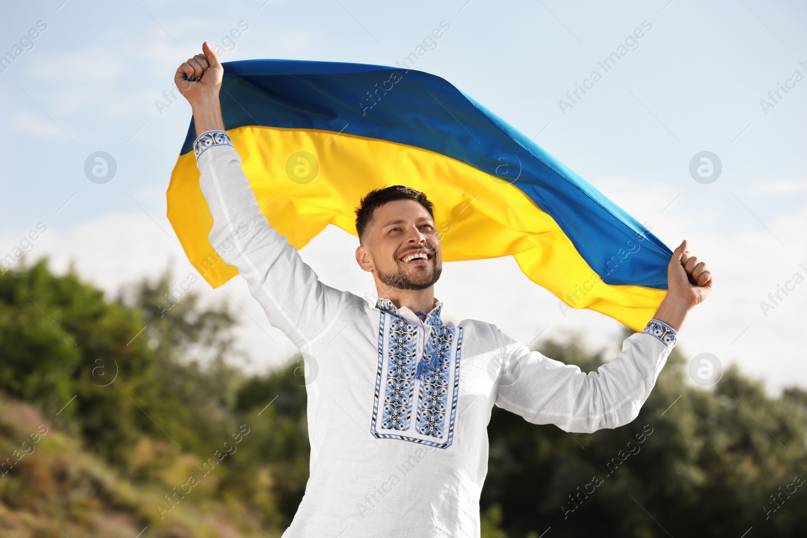 Photo of Man in vyshyvanka with flag of Ukraine outdoors