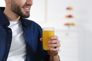 Man with delicious smoothie at home, closeup. Space for text