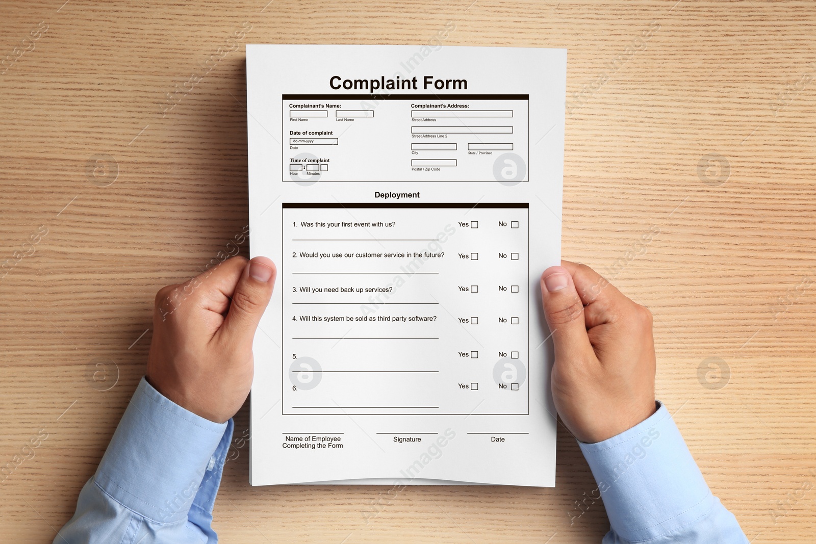 Image of Man holding complaint form at wooden table, top view