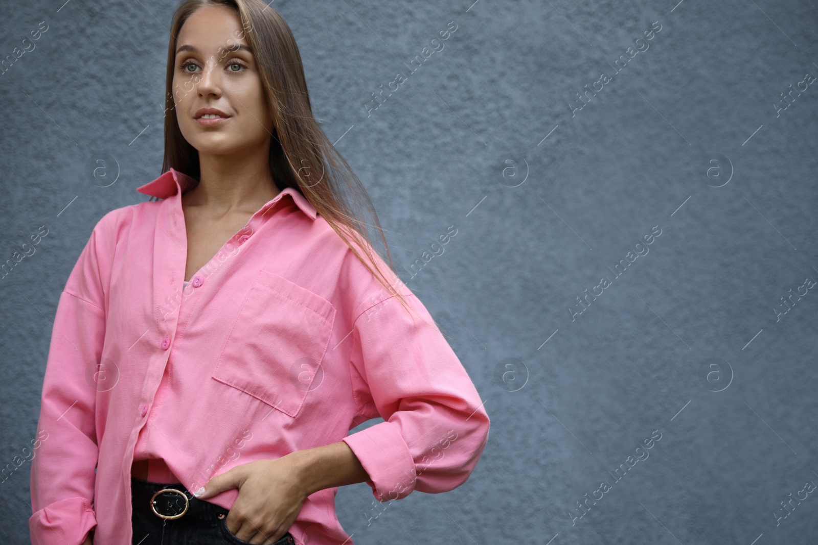 Photo of Beautiful young woman near grey wall, space for text