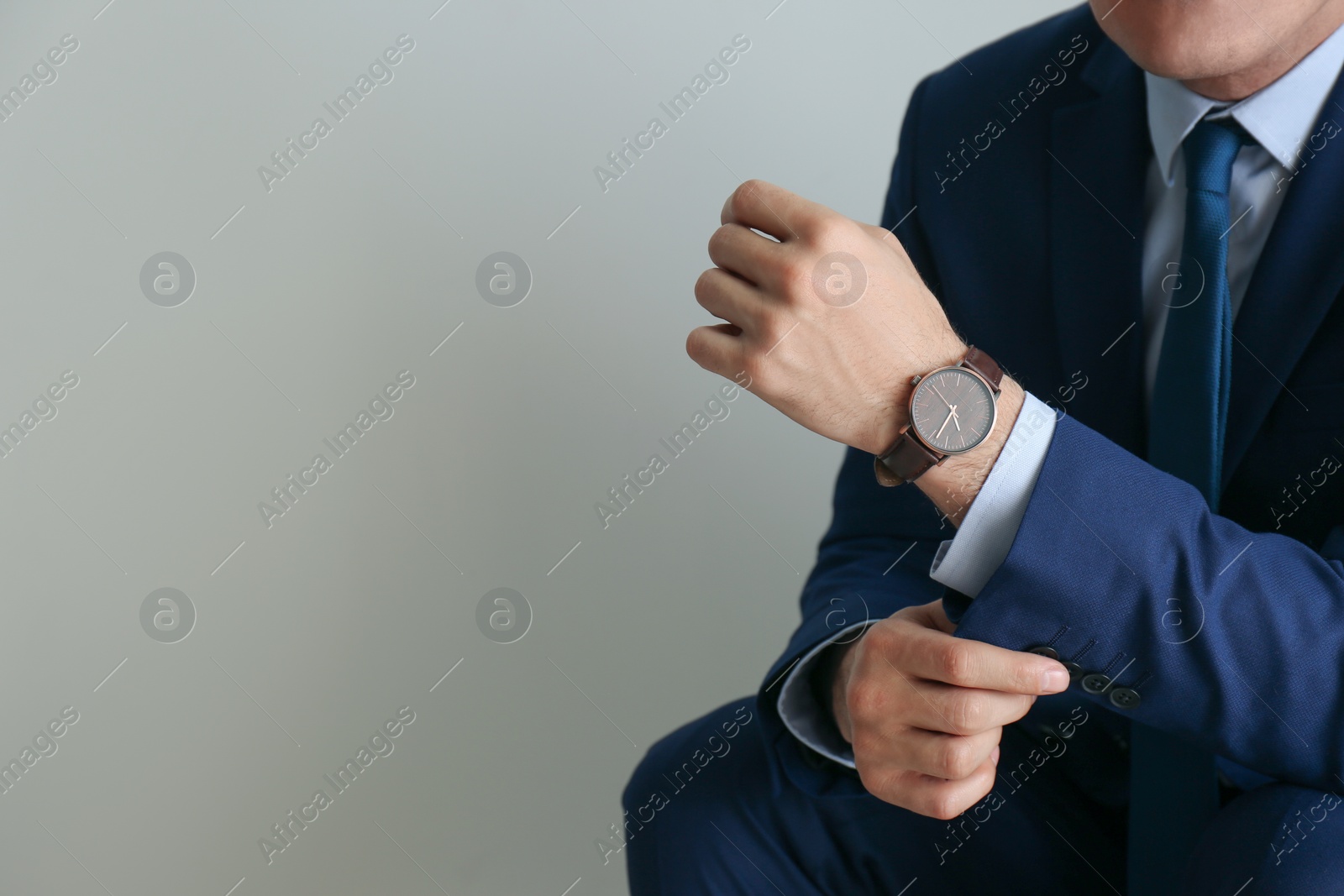 Photo of Businessman with luxury wrist watch on grey background, closeup. Space for text
