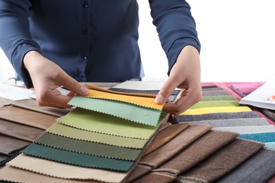 Young woman choosing among upholstery fabric samples, closeup. Interior design