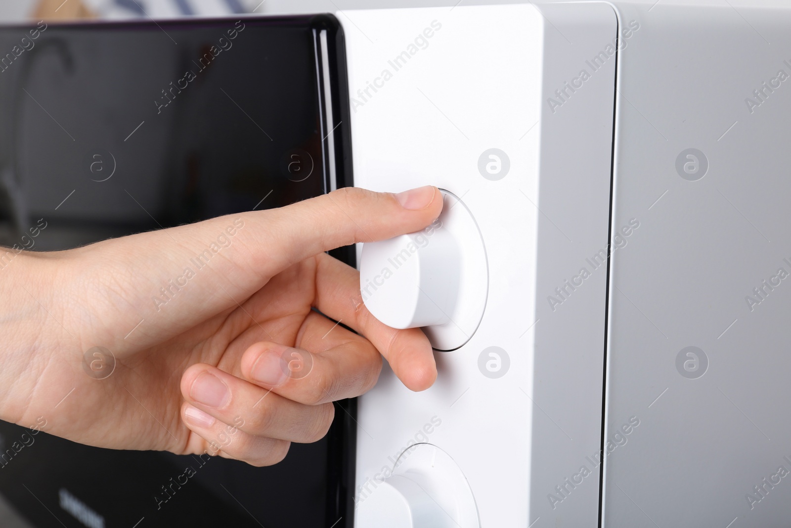 Photo of Woman adjusting microwave oven, closeup. Kitchen appliance