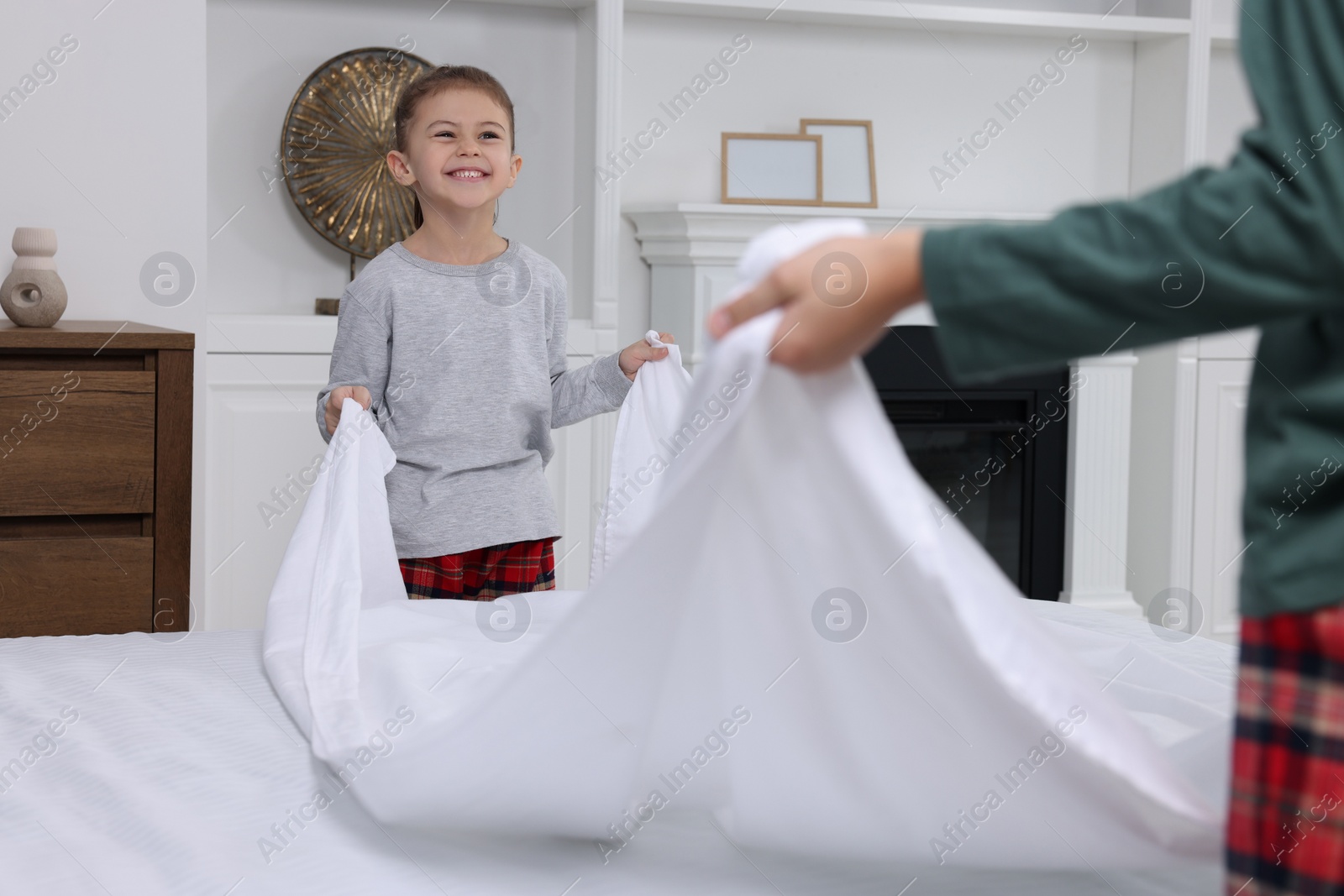 Photo of Brother and sister changing bed linens together in bedroom