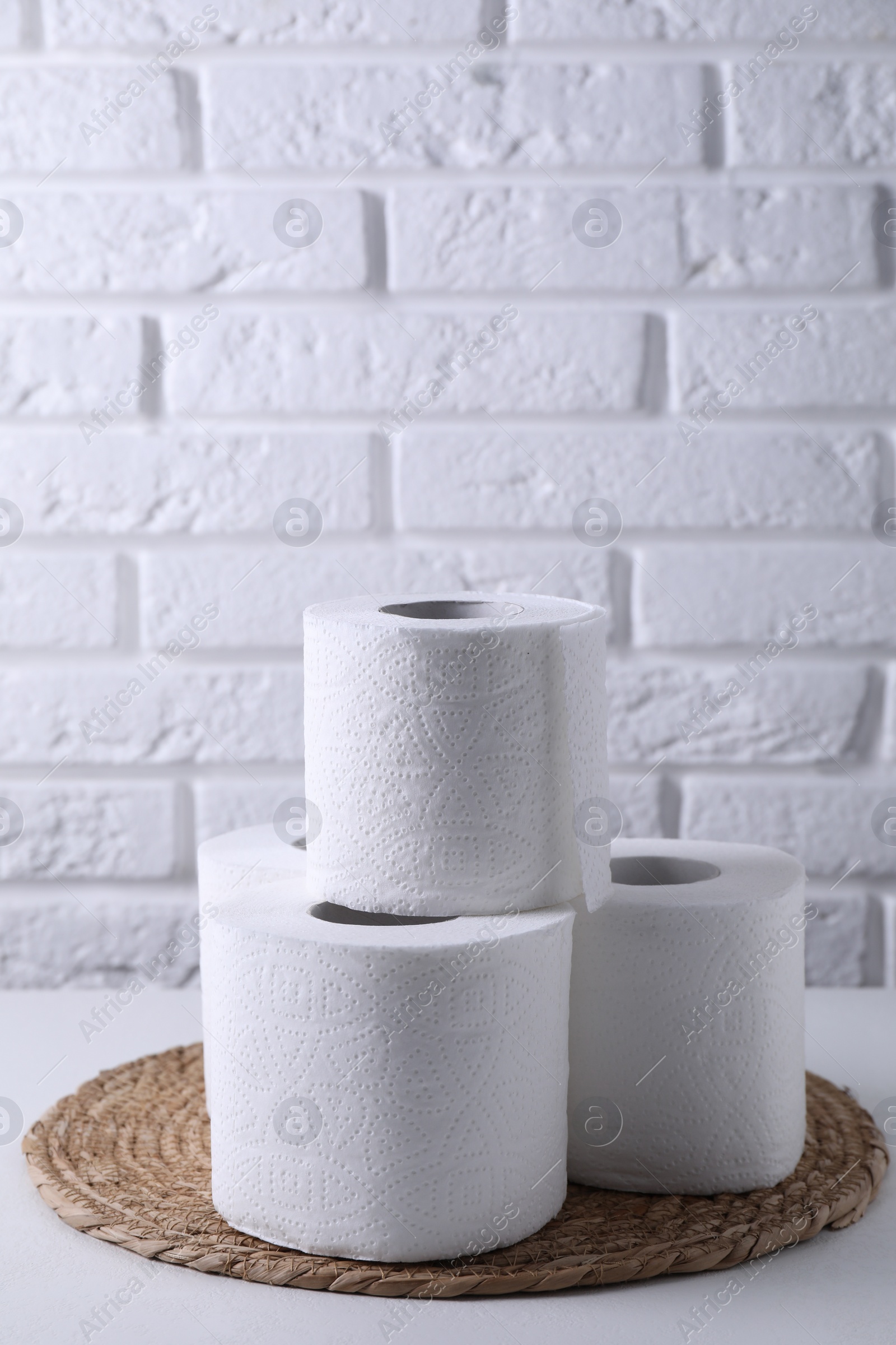 Photo of Toilet paper rolls on white table against brick wall