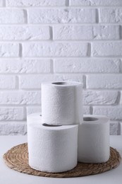 Toilet paper rolls on white table against brick wall