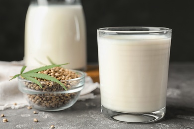 Composition with glass of hemp milk on grey table against black background, closeup