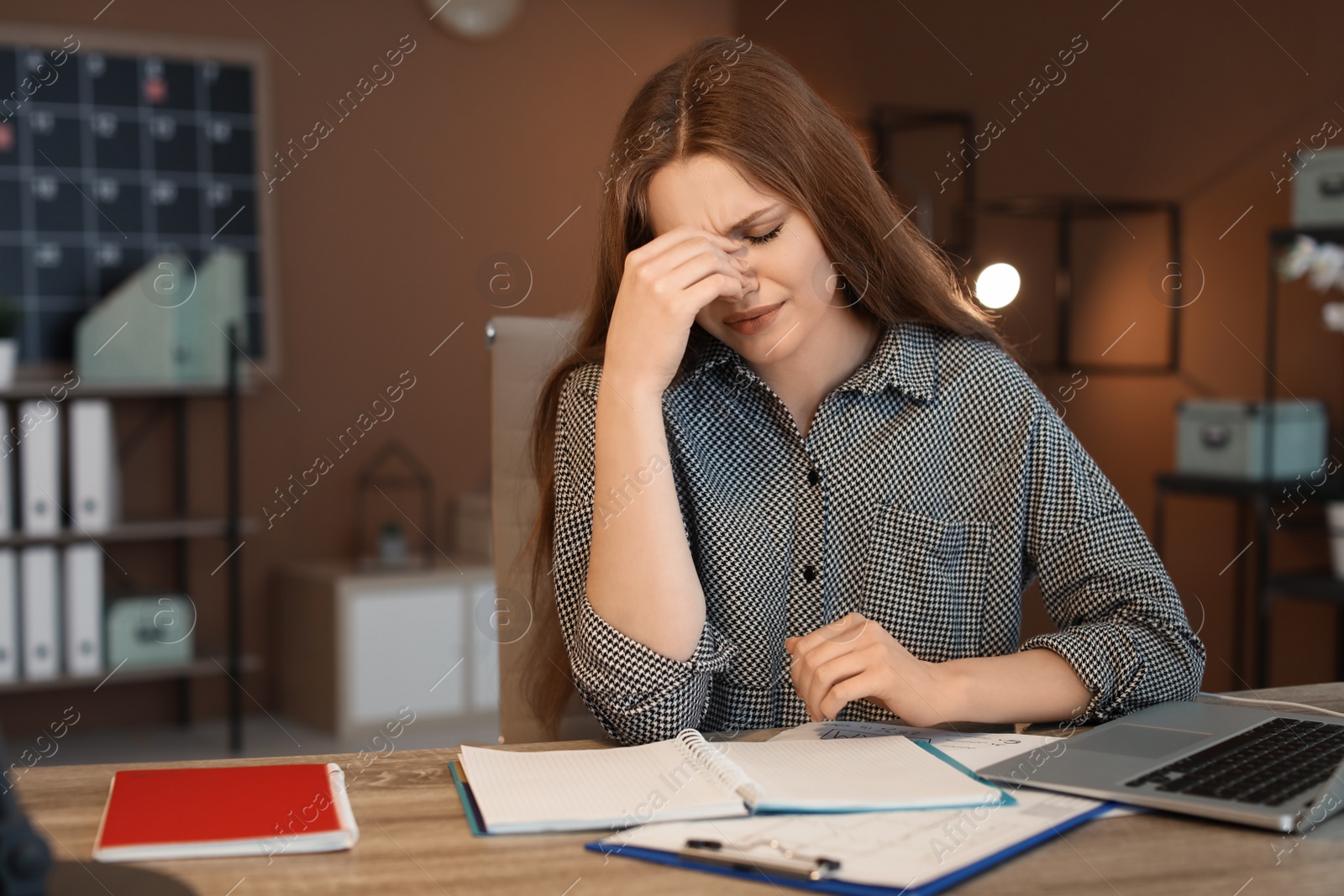 Photo of Overworked young woman with headache in office