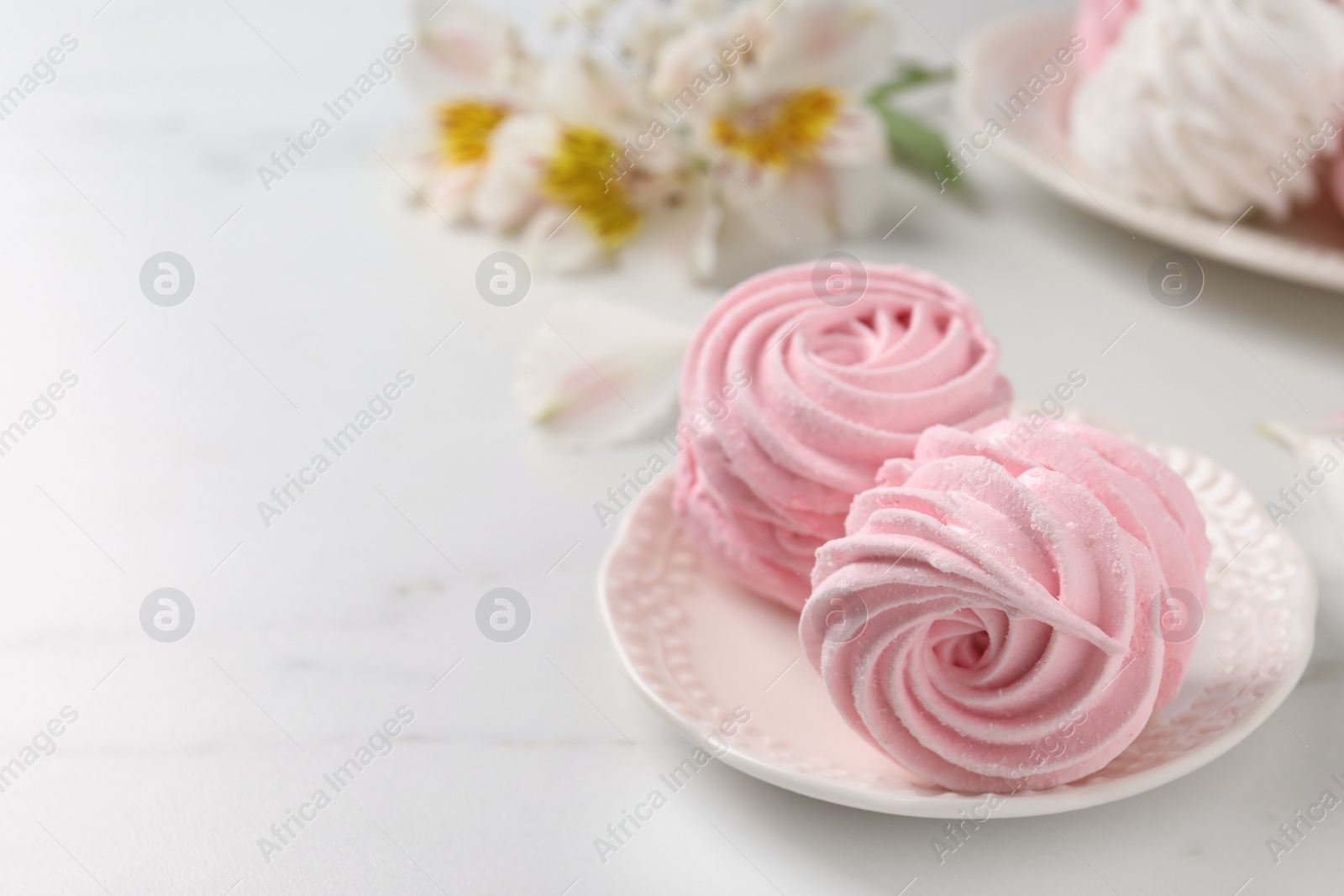 Photo of Plate with delicious pink zephyrs on white table, space for text