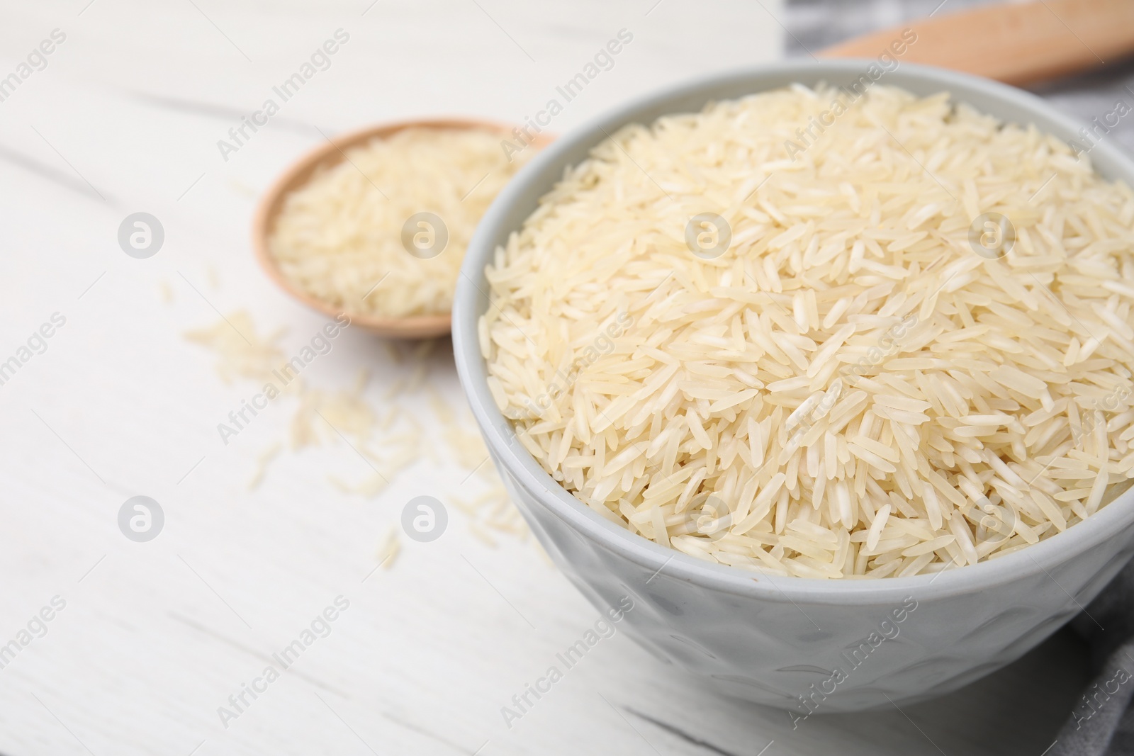 Photo of Raw rice in bowl on white wooden table, closeup. Space for text