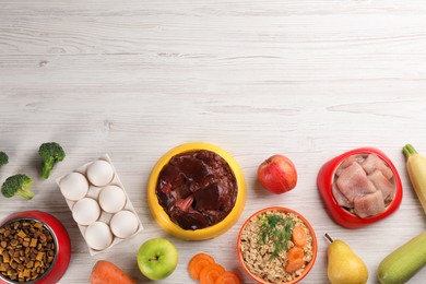 Photo of Pet food and natural ingredients on white wooden table, flat lay. Space for text