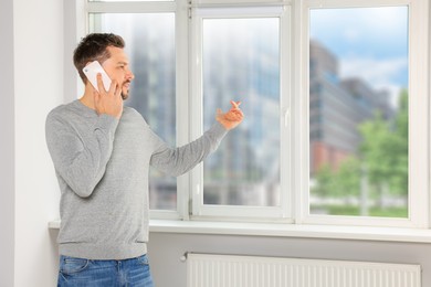 Photo of Man talking on phone near window indoors, space for text
