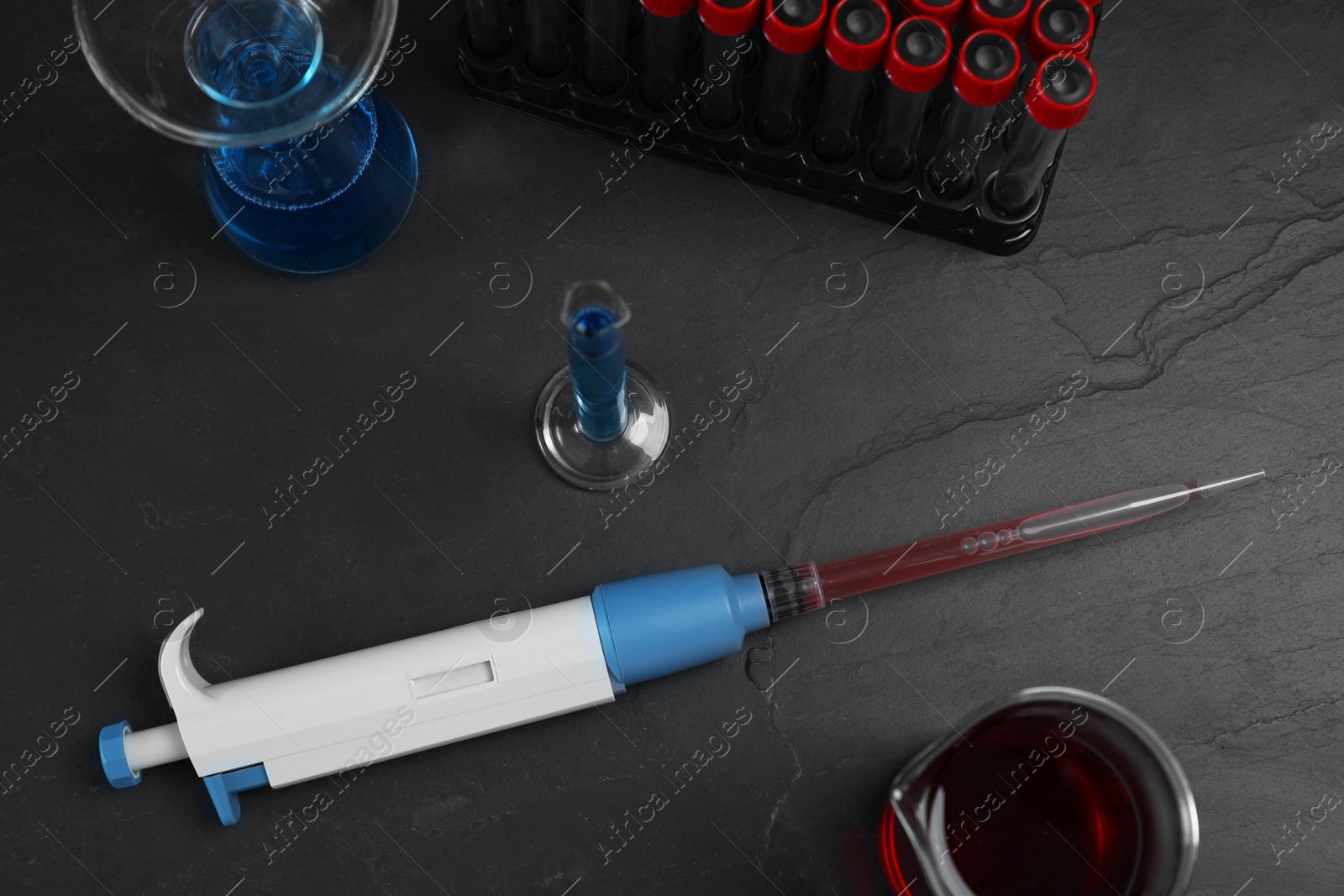 Photo of Laboratory analysis. Micropipette and different glassware on black table, flat lay