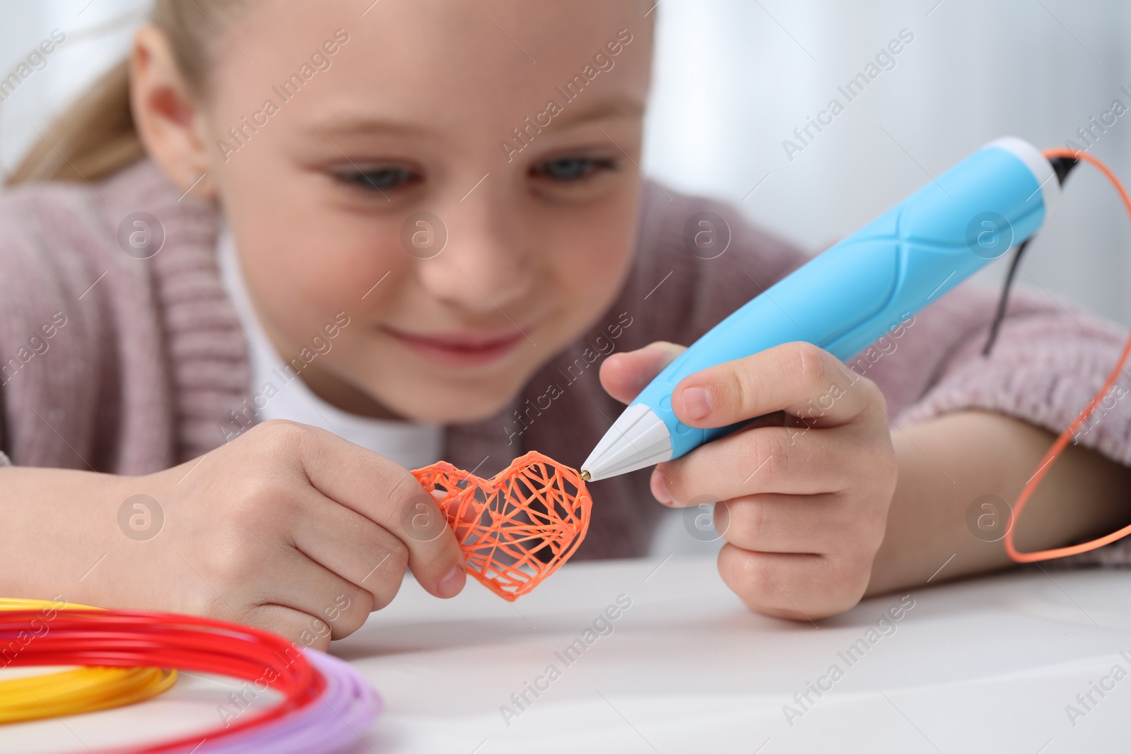 Photo of Girl drawing with stylish 3D pen at white table indoors, selective focus