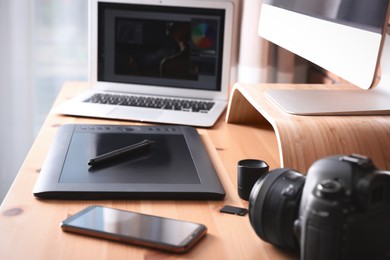 Photo of Modern retoucher's workplace with different digital devices on wooden table