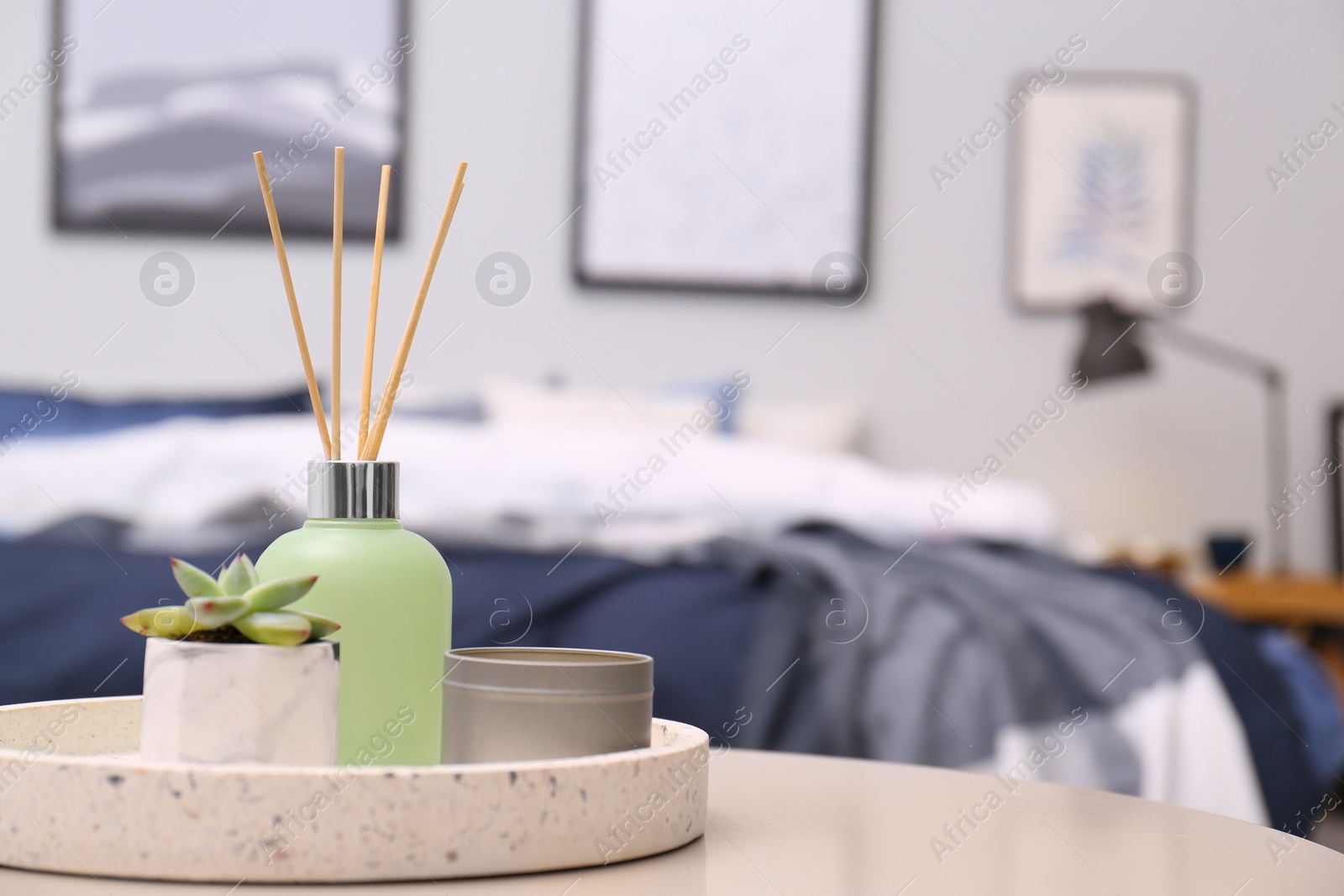 Photo of Aromatic reed air freshener, candle and houseplant on table in room. Space for text