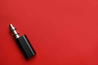 Photo of Electronic smoking device on red background, top view. Space for text