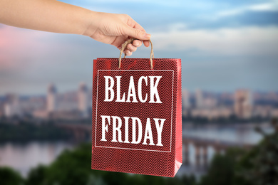 Woman holding shopping bag with text BLACK FRIDAY outdoors, closeup