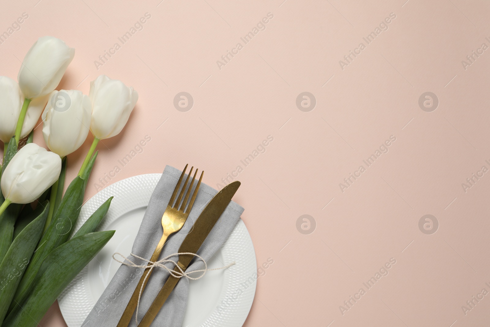 Photo of Stylish table setting with cutlery and tulips on pink background, flat lay. Space for text