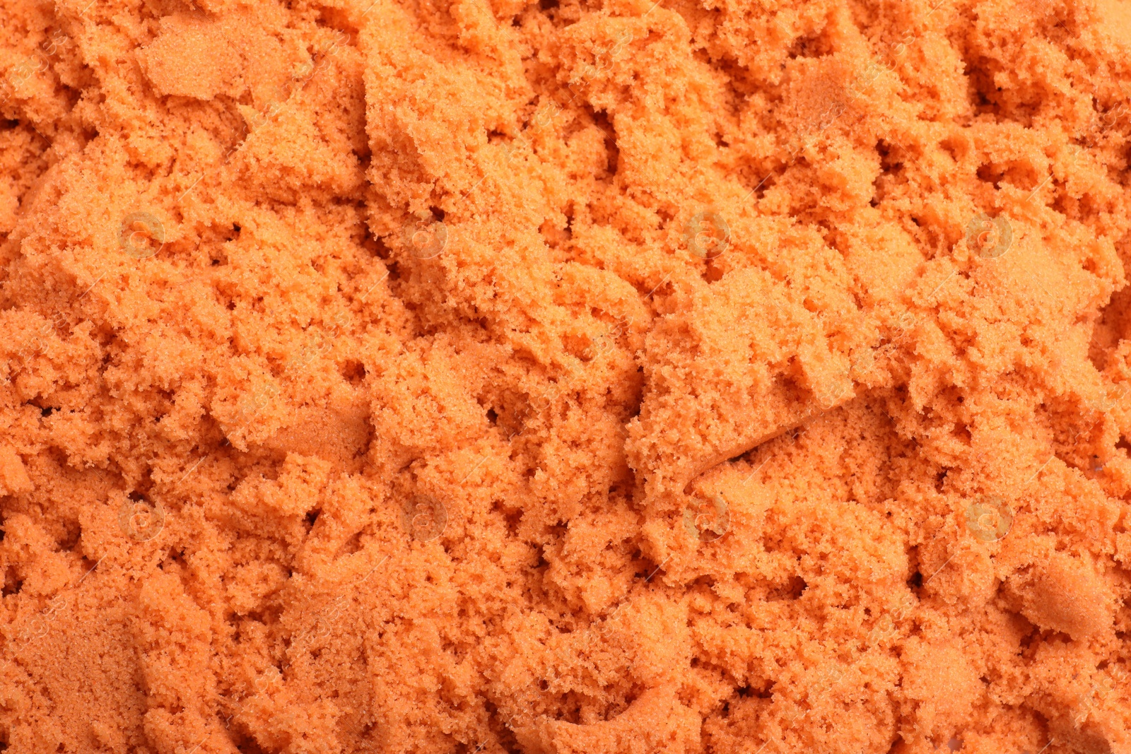 Photo of Orange kinetic sand as background, closeup view