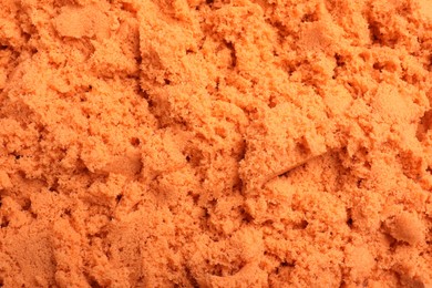 Orange kinetic sand as background, closeup view