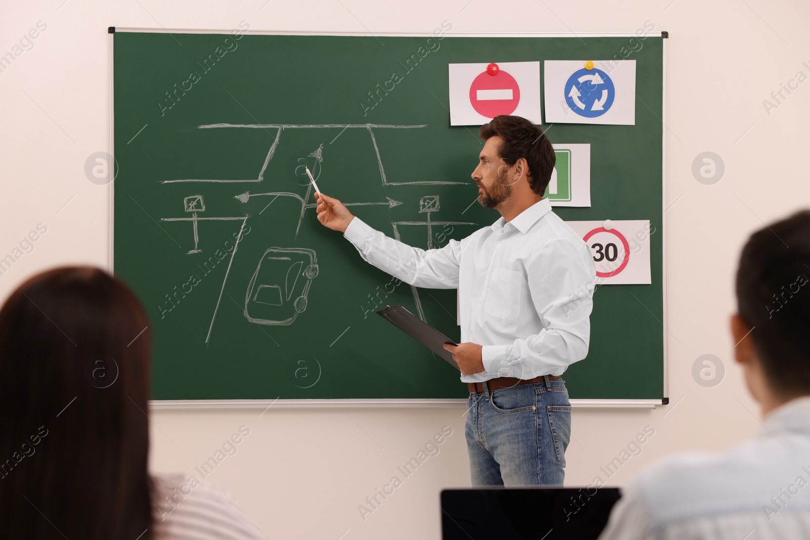 Photo of Teacher explaining traffic rules to audience during lesson in driving school