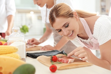 Female chef preparing meat on wooden board at table