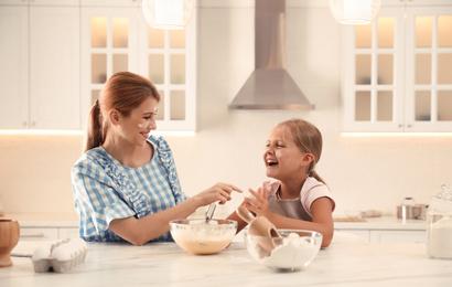 Photo of Mother and daughter making dough together in kitchen