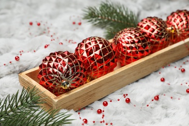 Beautiful Christmas baubles in box on white fur, closeup