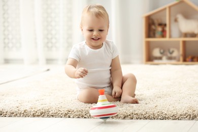 Children toys. Cute little boy playing with spinning top on rug at home