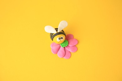 Photo of Bee with flower made from plasticine on orange background. Children's handmade ideas