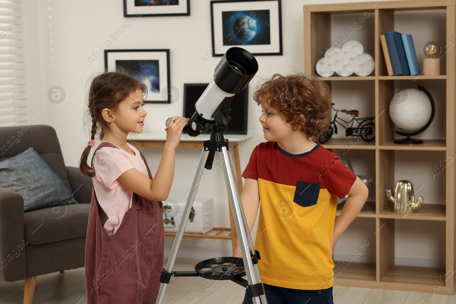 Photo of Cute little children using telescope to look at stars in room