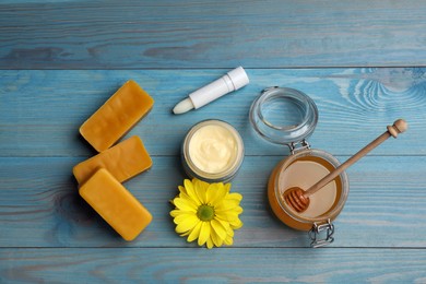 Photo of Flat lay composition with beeswax and cosmetic products on blue wooden table
