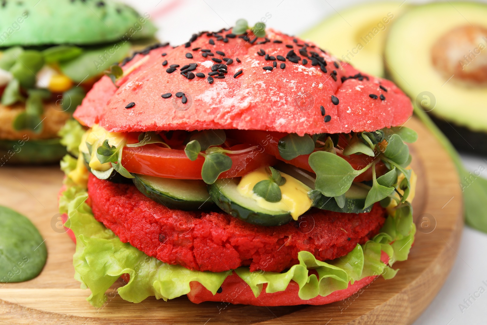 Photo of Tasty pink vegan burger with vegetables, patty and microgreens on white table, closeup